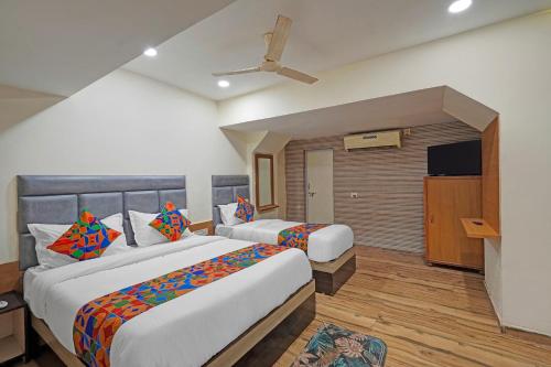 Una habitación de hotel con dos camas y un televisor. en FabHotel Rajtilak, en Ahmedabad