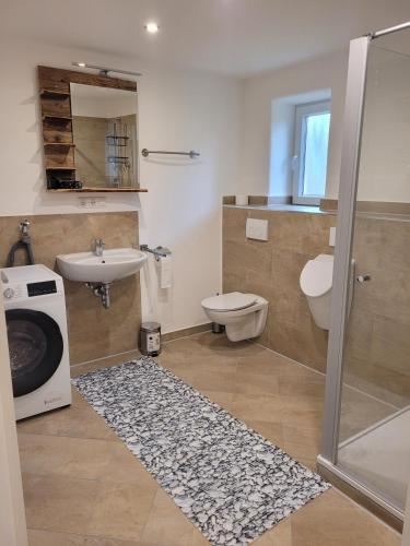 a bathroom with a sink toilet and a washing machine at Ferienwohnung Lindenblüte in Eggenthal