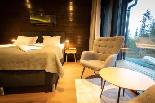 ein Schlafzimmer mit einem Bett und einem Stuhl und einem Fenster in der Unterkunft Ruka Trek Gasthaus & Hard Trek Café in Kuusamo