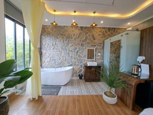 a bathroom with a tub and a stone wall at Khu vườn của Nàng Đà Lạt - Le Jarden De Nàng in Da Lat