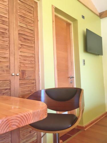 a room with a table and two chairs and a television at Tribu Malen Apartamentos in Temuco