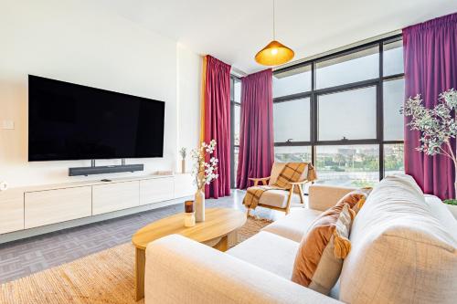 a living room with a flat screen tv and purple curtains at Fantastic Rooftop Pool - Full Canal Views - Spacious 1 BDR Designed by Designer - 5 min walk from Space42 Arena in Abu Dhabi