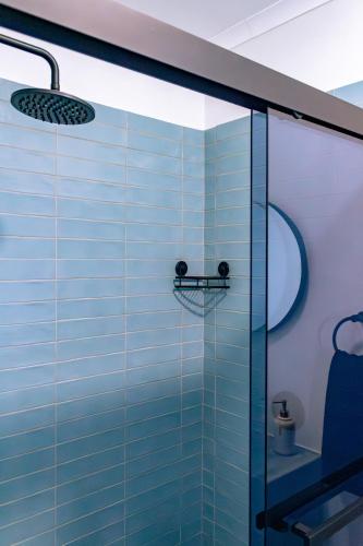 a bathroom with a glass shower with blue tiles at S Haven Luxury Self Catering Apartment in Franskraalstrand