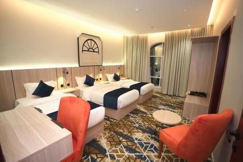 ein Hotelzimmer mit zwei Betten und zwei Stühlen in der Unterkunft فندق ذا اس سكوير المطار The S Square Airport Hotel in Dschidda