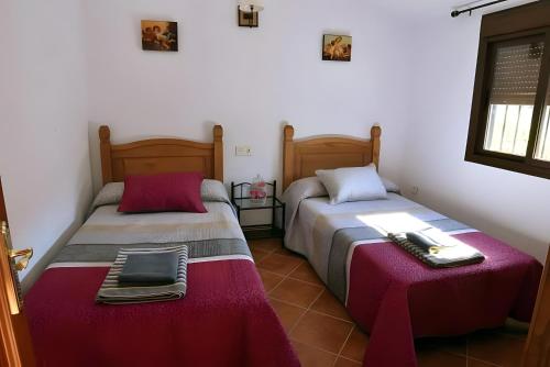 Zwei Betten in einem Zimmer mit einem Tisch und einem Laptop in der Unterkunft Caminito Del Rey Valley House in Valle de Abdalagís