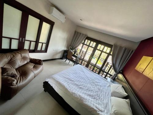 a bedroom with a bed and a couch and windows at Sea view room in Nathon Bay