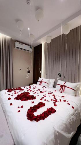 a bed covered in red roses on a white bed at البرج للشقق المخدومة 2 in Al Nairyah