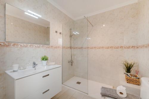 a white bathroom with a shower and a sink at El Gin in Playa Blanca