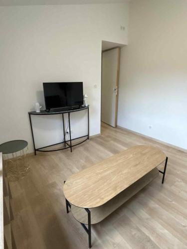 a living room with a table and a tv at Appartement Peronne Centre in Péronne