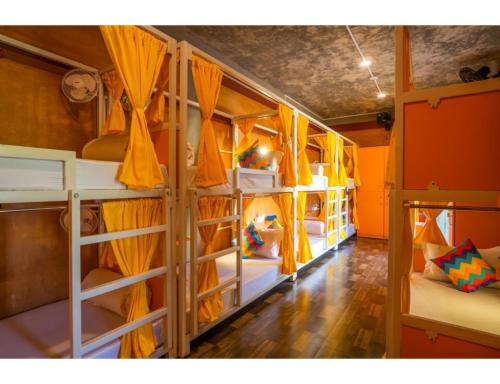 a room with four bunk beds with yellow curtains at goSTOPS Pondicherry Near Auroville in Auroville