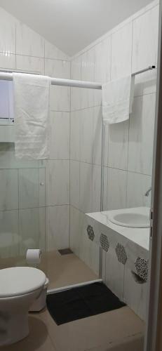 a white bathroom with a toilet and a sink at Chácara e Pousada Aeroporto in Andradina