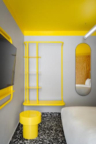 une chambre jaune avec un lit et un tabouret jaune dans l'établissement Beauquartier - Chemin Vert, à Paris
