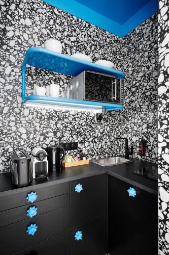 une cuisine avec des placards noirs et une étagère bleue dans l'établissement Beauquartier - Chemin Vert, à Paris