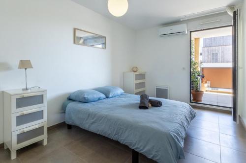 een slaapkamer met een bed met blauwe lakens en een raam bij La Terrasse de Duranne - Accès rapide TGV Aéroport in Aix-en-Provence