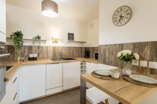 een keuken met een houten tafel en een klok aan de muur bij La Terrasse de Duranne - Accès rapide TGV Aéroport in Aix-en-Provence