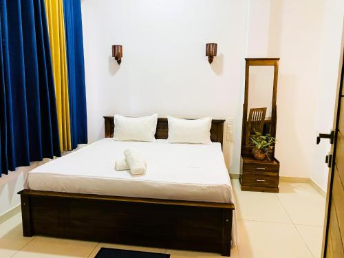 a bedroom with a bed with white sheets and a mirror at Anthony's Villa in Galle