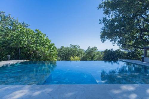 a swimming pool with blue water and trees in the background at Appartement sur Domaine Aix - Piscine Tennis - Mozart in Aix-en-Provence