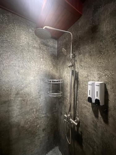 a shower in a bathroom with a light on the wall at Downtime Hotel Phnom Penh in Phnom Penh
