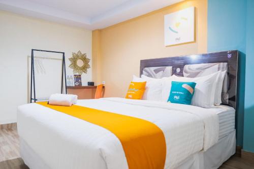una camera da letto con un letto grande con cuscini colorati di Sans Hotel Cemara Asri Medan a Pulauberayan Dadap