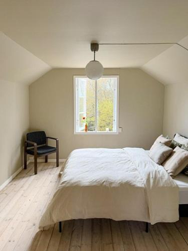 a bedroom with a large white bed and a window at Classic Swedish Wooden House Near Sea And Forest in Svängsta