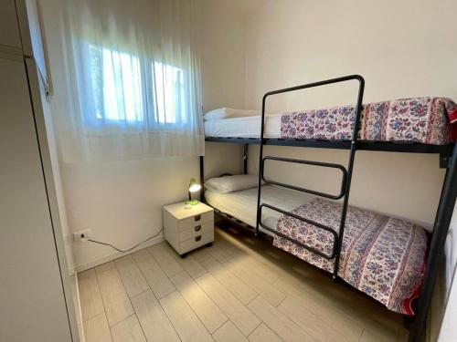 Habitación pequeña con 2 literas y lámpara. en Holiday home with garden and shared pool, en Porto Santa Margherita