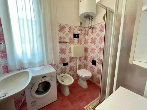 y baño con lavamanos y lavadora. en Holiday home with garden and shared pool, en Porto Santa Margherita