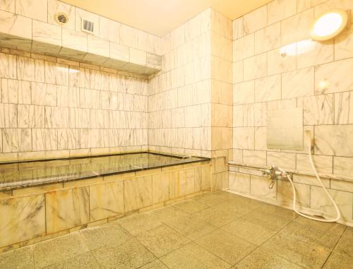 a tiled room with a shower and a sink at Kawatatsu in Nozawa Onsen