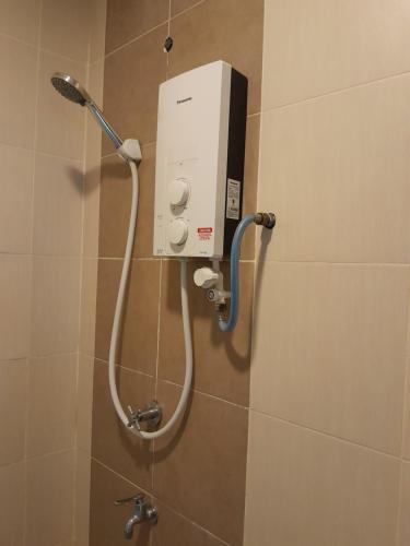 a shower in a bathroom with a shower head at Manhattan Suites, Itcc in Penampang