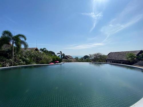 a large swimming pool with a view of the ocean at Sea top room in Amphoe Koh Samui