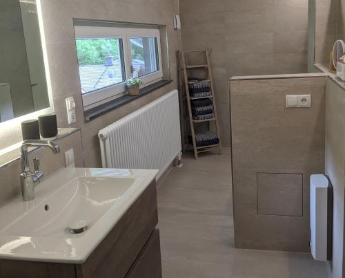 a bathroom with a white sink and a window at Ferienhaus Schieferterrasse - Waldsee Rieden - in Rieden