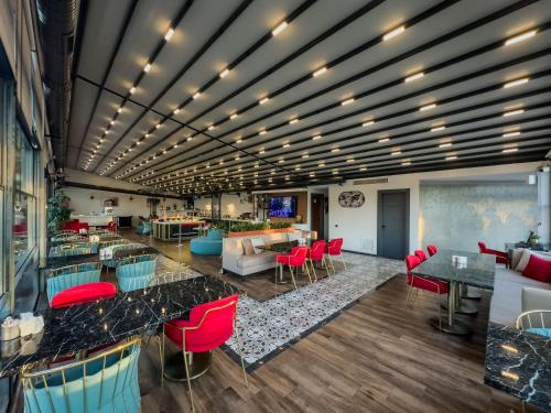 a lobby with red chairs and tables in a room at Leaf Port Hotel in Antalya