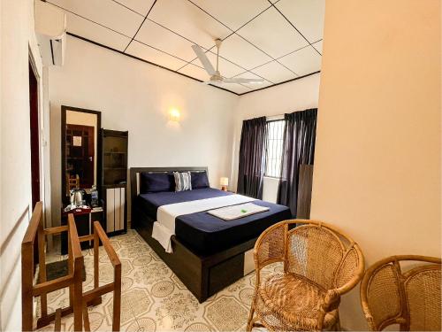 a bedroom with a bed and a chair in it at RIVINSON Negombo in Negombo