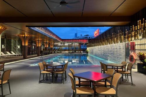 a pool with tables and chairs next to a building at Vivatel Kuala Lumpur in Kuala Lumpur