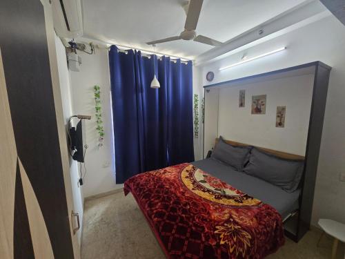 Schlafzimmer mit einem Bett mit blauen Vorhängen in der Unterkunft Studio Apartment - 4pax - Hiranandani Estate in Thane
