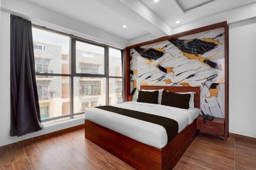 a bedroom with a large bed with a painting on the wall at Super Townhouse Whitefield Railway Station Formerly Kadugudi Whitefield in Bangalore