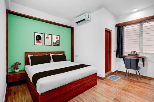 a bedroom with a large bed and a desk at Super Townhouse Whitefield Railway Station Formerly Kadugudi Whitefield in Bangalore