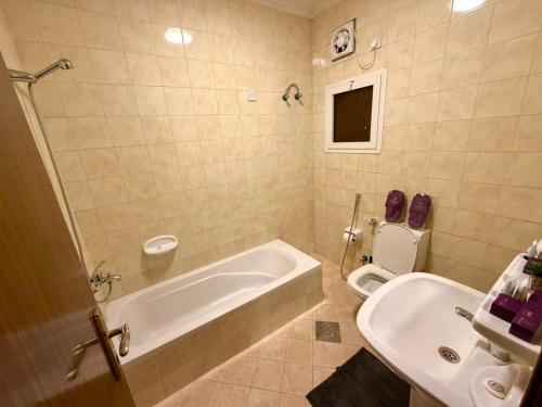 a bathroom with a tub and a toilet and a sink at D3S 3BR Apartment in Makkah