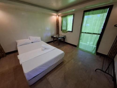 a bedroom with a white bed and a window at Izzahjay homestay in Burgos