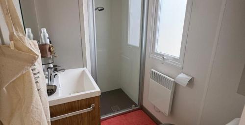 een witte badkamer met een wastafel en een raam bij Mobil Home 40m2, Bonne Anse Siblu 4 étoiles in Les Mathes
