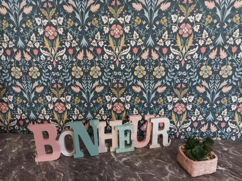 a room with a floral wall with a sign and a plant at Appartement Détente in Chamole