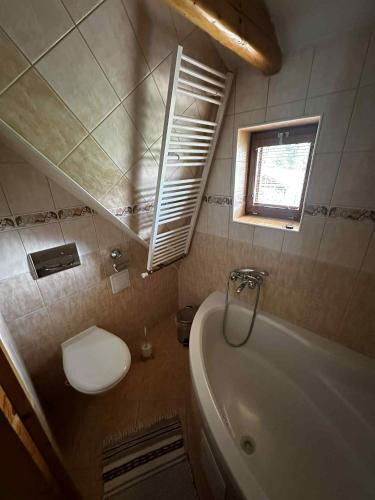 Un baño con bañera, inodoro y ventana. en Chatka Zuberec, en Tvrdošín