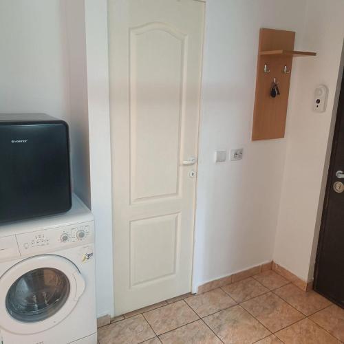 eine Waschküche mit einer Waschmaschine und einem TV in der Unterkunft Hunedoara Central Stay in Hunedoara