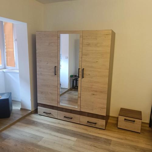 einen Holzschrank mit einem Spiegel im Zimmer in der Unterkunft Hunedoara Central Stay in Hunedoara