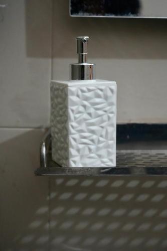a white soap dispenser sitting on a shelf at The Cozy Nest in Rishīkesh