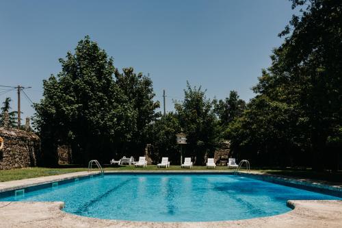 a swimming pool with chaises and chairs in a yard at Pazo Almuzara in Boborás