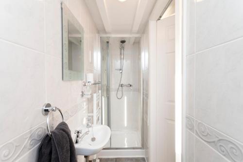 a white bathroom with a shower and a sink at Cedar Place in Southwell in Southwell