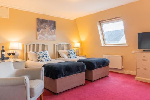 a bedroom with two beds and a tv and a couch at The Moorings Hotel & Seafood Restaurant in Portmagee
