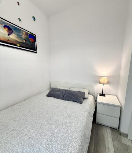 a white bedroom with a bed and a night stand at theApartments Manufaktura in Łódź
