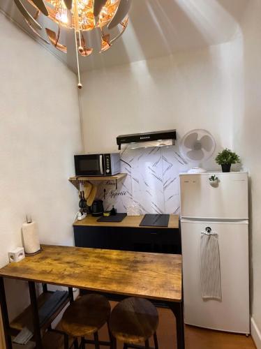 a small kitchen with a table and a refrigerator at Studio moderne et chaleureux au coeur de Geneve - parfait pour courts sejours in Geneva