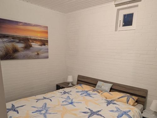 a bedroom with a bed with a painting on the wall at Ferienhaus LouJa in Butjadingen